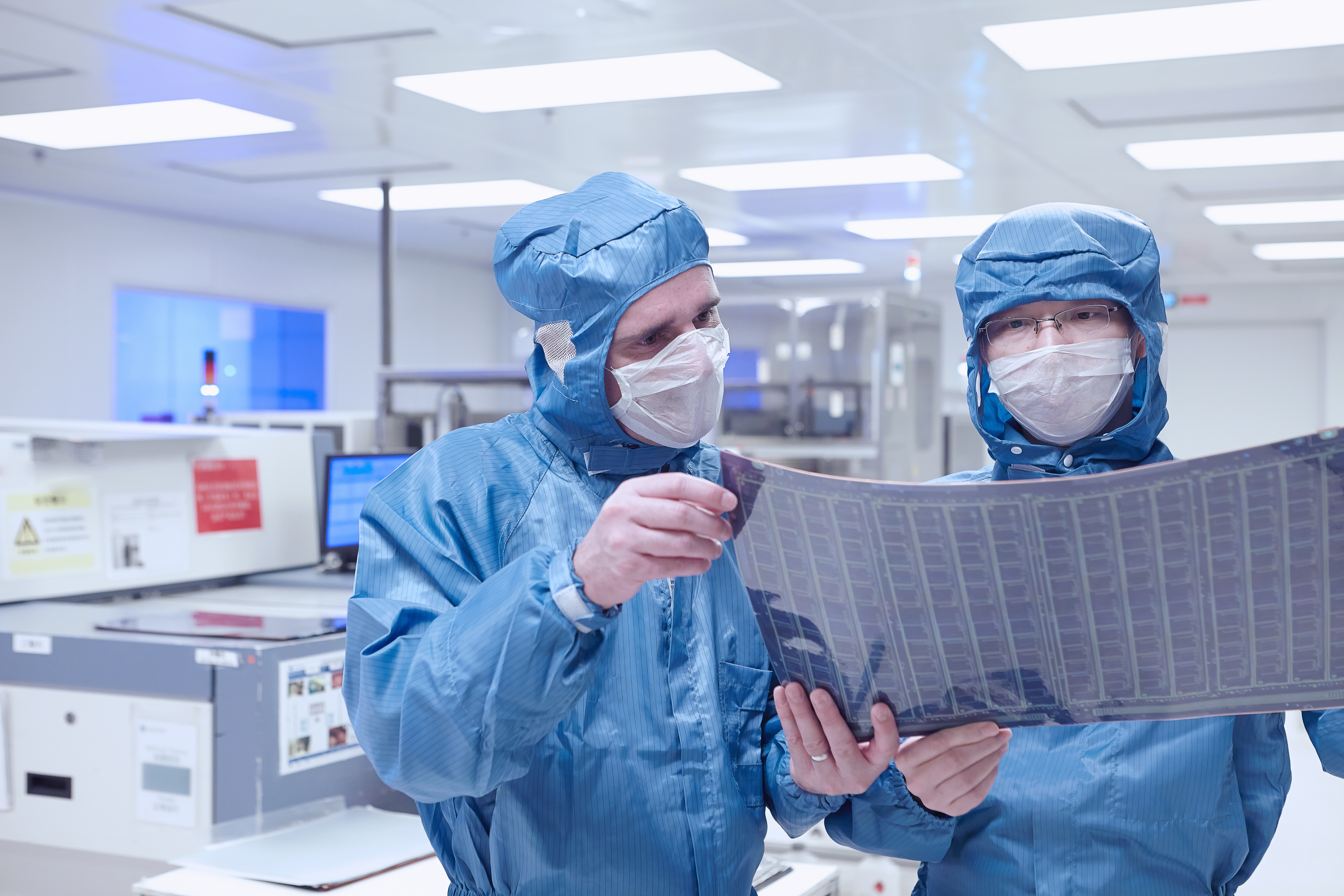 Werkende mensen in beschermende kleding in een cleanroom omgeving